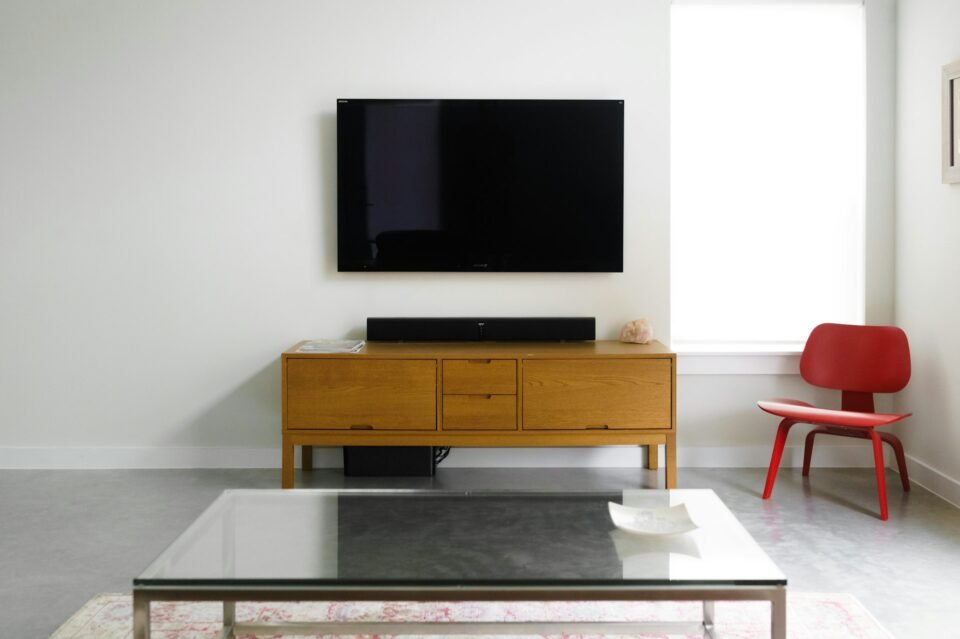 Flat-screen TV mounted on a living-room wall above a wooden cabinet